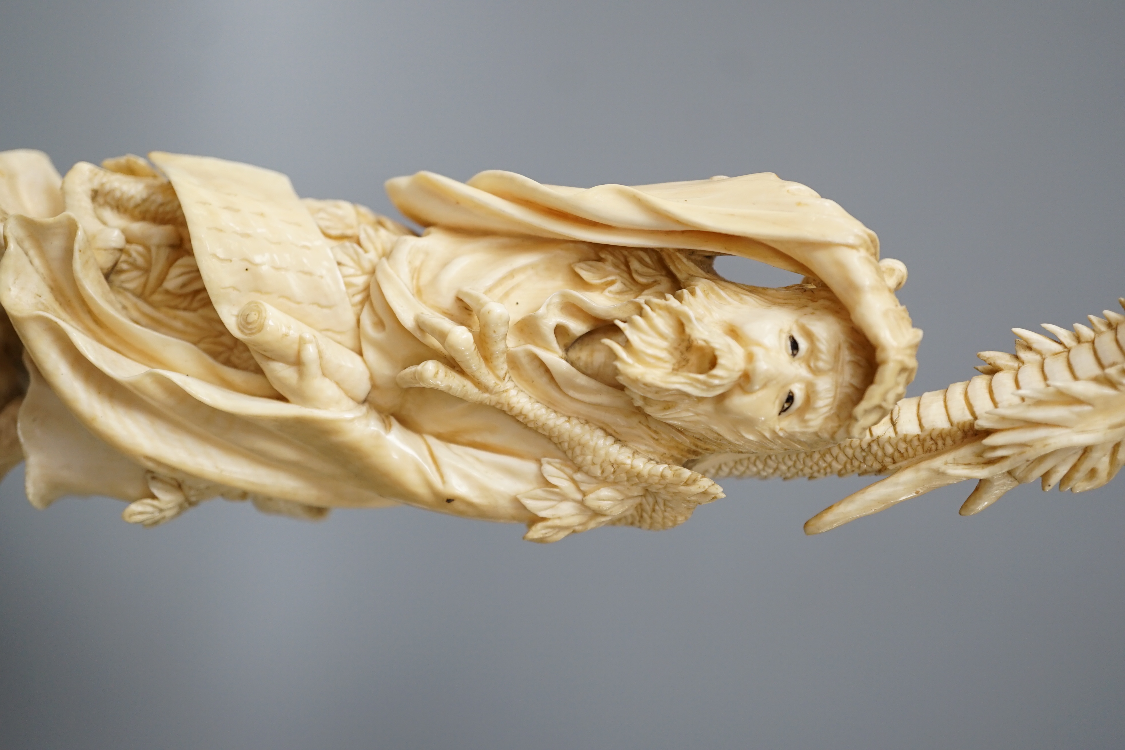 A Japanese ivory okimono of Shoshi Sennin and a dragon, early 20th century, signed, associated wood stand, 24cm excl stand
